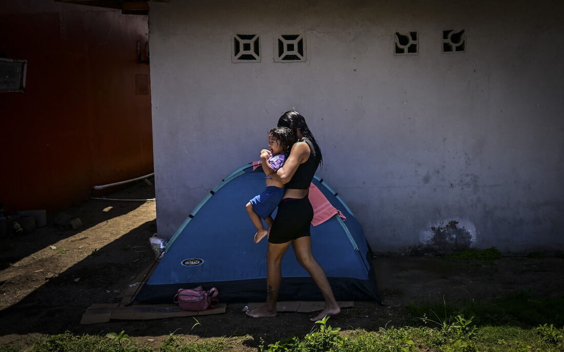 Uma mulher migrante acampa com sua filha enquanto espera para pegar um barco para a Colômbia