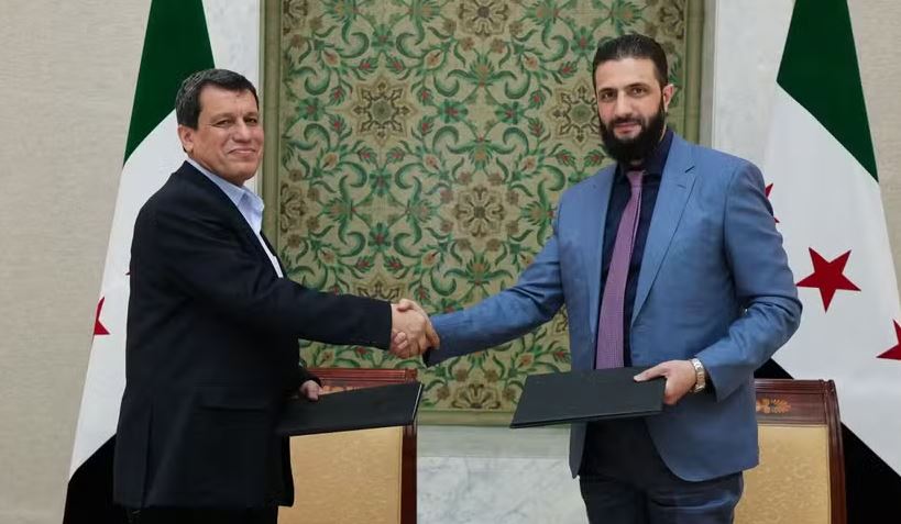 Presidente interino da Síria, Ahmed al-Sharaa, aperta a mão do comandante-chefe das Forças Democráticas Sírias, Mazloum Abdi, após acordo