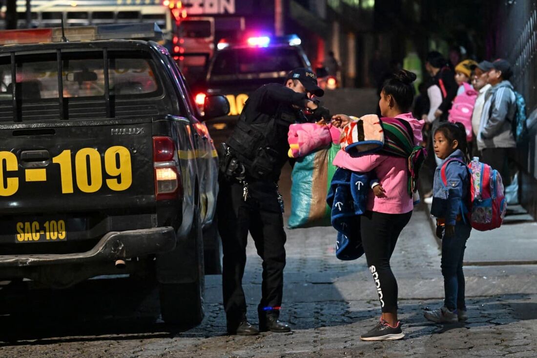 Um policial ajuda pessoas que chegam para abrigo após evacuar sua aldeia devido a uma erupção do vulcão Fuego, em Alotenango