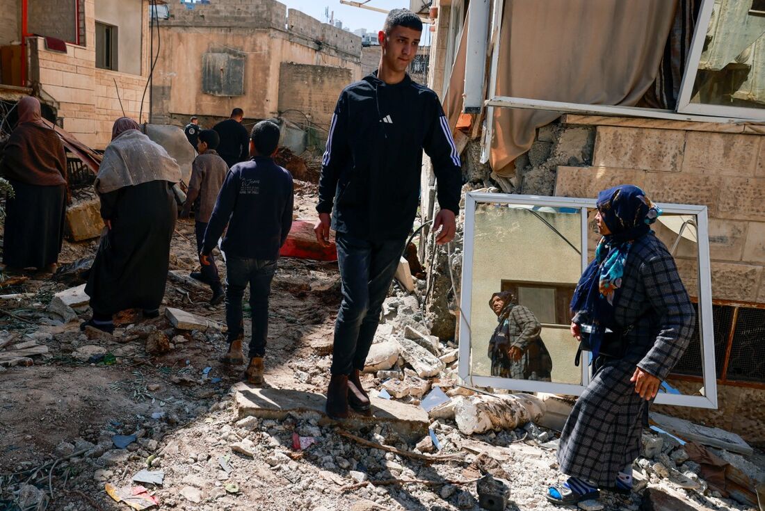 Palestinos inspecionam a destruição após um ataque israelense no início do dia no bairro oriental da cidade de Jenin, na Cisjordânia ocupada por Israel