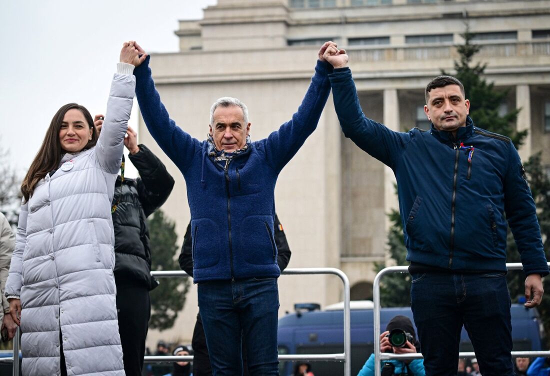 Anamaria Gavrila (E), líder do Partido dos Jovens (POT), Calin Georgescu (C), ex-candidato presidencial, e George Simion (D), líder da Aliança para a Unidade dos Romenos (AUR) posam durante um comício de apoio a Georgescu em Bucareste
