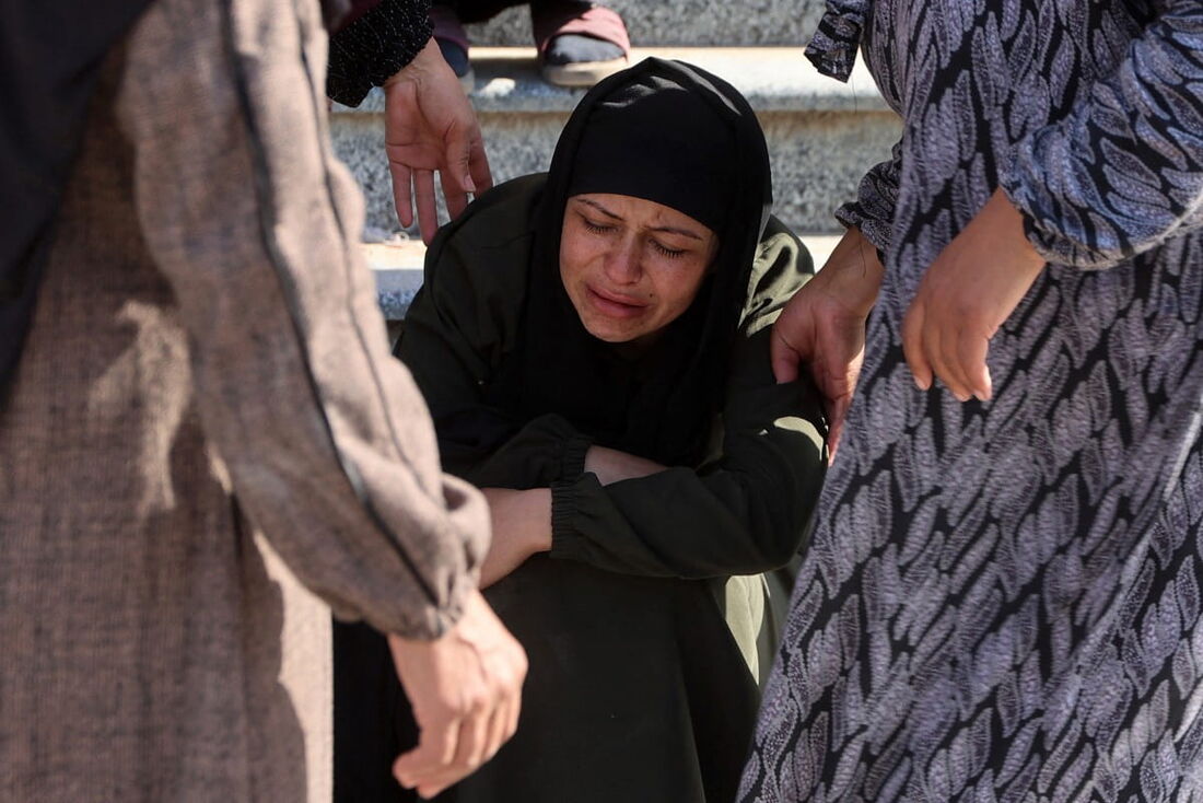 Uma mulher é consolada enquanto se despedem dos corpos das vítimas mortas pelo bombardeio israelense em Gaza