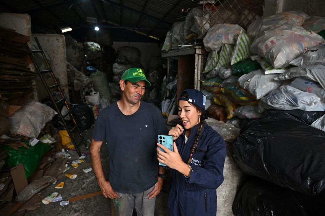 Criadora de conteúdo para redes sociais, Sara Samaniego, conhecida como "Marce, a recicladora" (D), grava um vídeo com Rafael Chala em um depósito de reciclagem em Bogotá em 26 de fevereiro de 2025. 