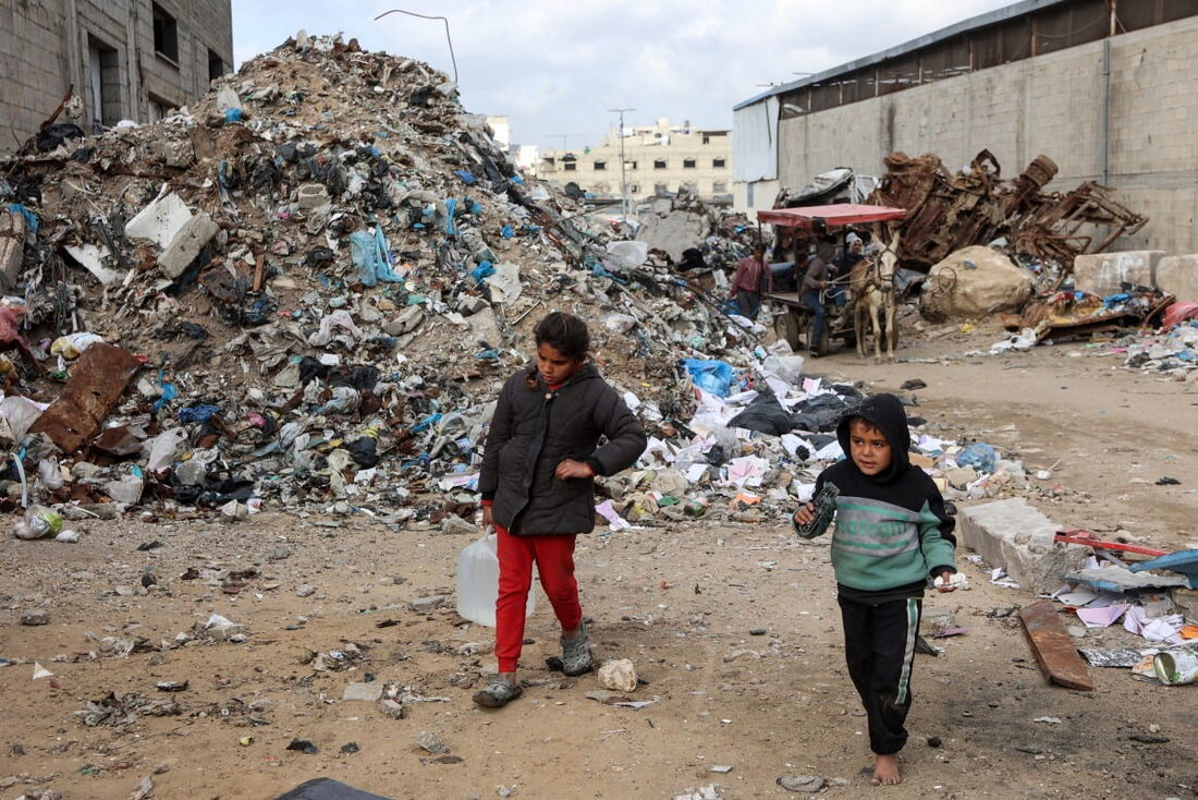 Crianças caminham em um acampamento abrigando palestinos deslocados, montado em um aterro sanitário na área de Yarmuk, na Cidade de Gaza