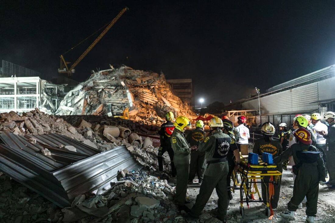 Equipes de resgate chegam com uma maca para evacuar um homem ferido em um canteiro de obras onde um prédio desabou em Bangkok em 28 de março de 2025, após um terremoto.