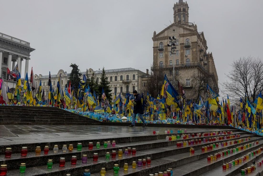 O homem caminha entre velas expostas no memorial improvisado para os combatentes ucranianos e estrangeiros na Praça da Independência em Kiev
