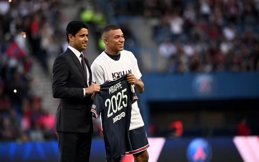 Mbappé (à direita) posa ao lado do presidente do PSG, Nasser Al-Khelaifi, diretamente ligado ao governo do Catar AFP
