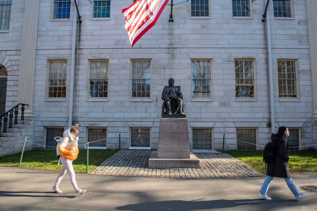 Pessoas caminham pelo pátio da Universidade Harvard em Cambridge, Massachusetts