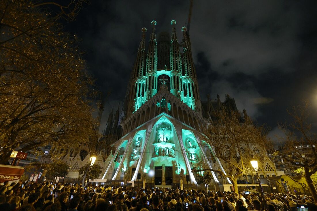  Pessoas assistem a um espetáculo de luzes projetado na fachada da Basílica da Sagrada Família, do arquiteto espanhol Antoni Gaudí, marcando o início da Semana Santa, em Barcelona