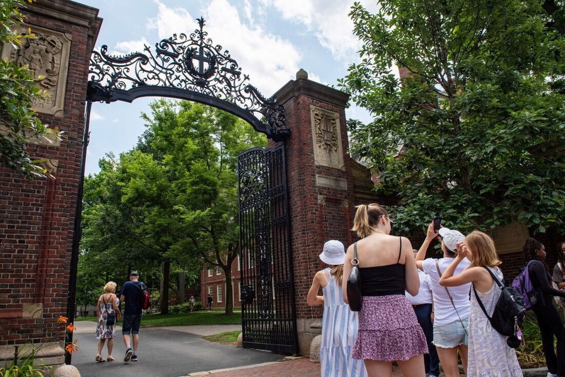 Pessoas tiram fotos na entrada do Harvard Yard em Cambridge, Massachusetts