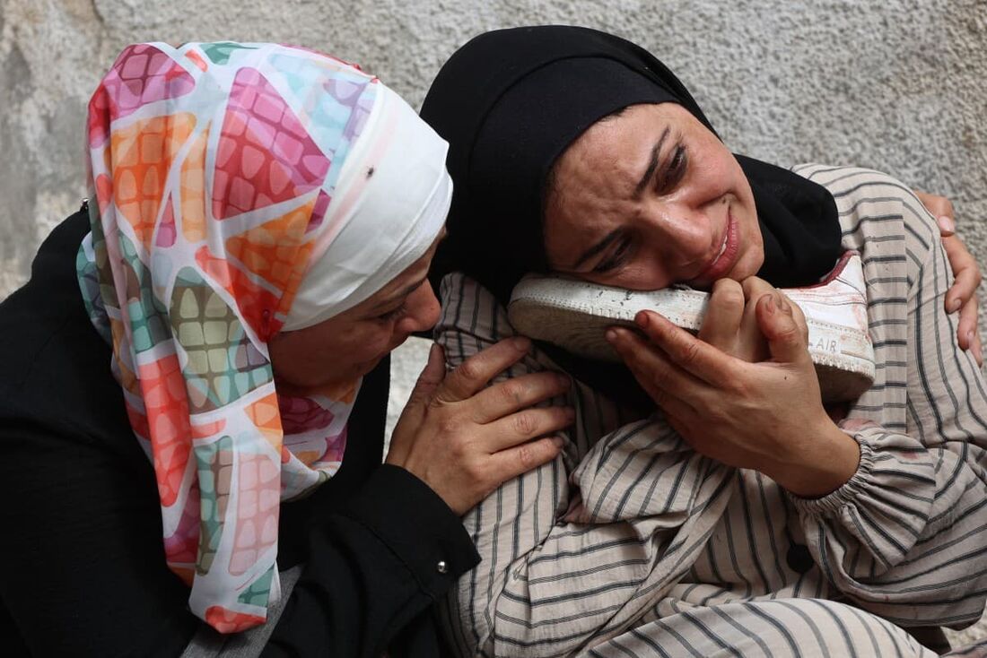 Uma mulher palestina chora enquanto segura o sapato manchado de sangue de um ente querido, que foi morto durante um ataque israelense na rua Al-Jalaa, no hospital Al-Shifa, na Cidade de Gaza
