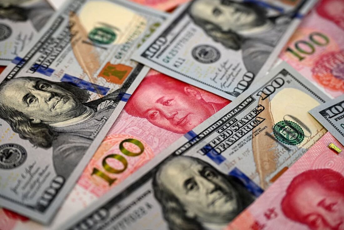 Notas chinesas de 100 yuans (vermelhas) e notas de 100 dólares americano