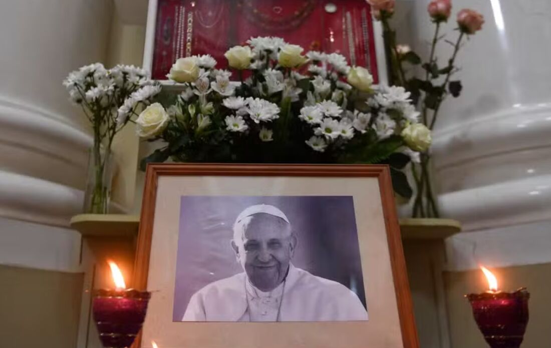 Velas são acesas em frente a um retrato do Papa Francisco em igreja, em São Petersburgo, em 21 de abril de 2025