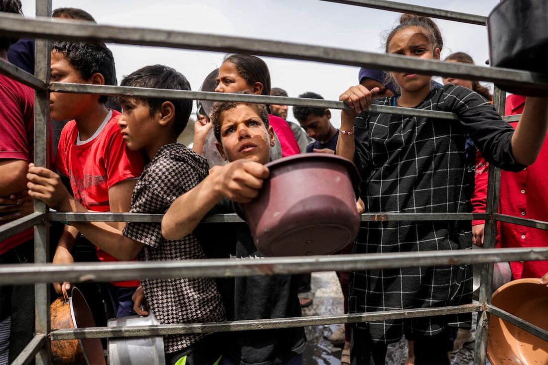 Crianças fazem fila com panelas para receber refeições beneficentes de uma cozinha em Beit Lahia, no norte da Faixa de Gaza