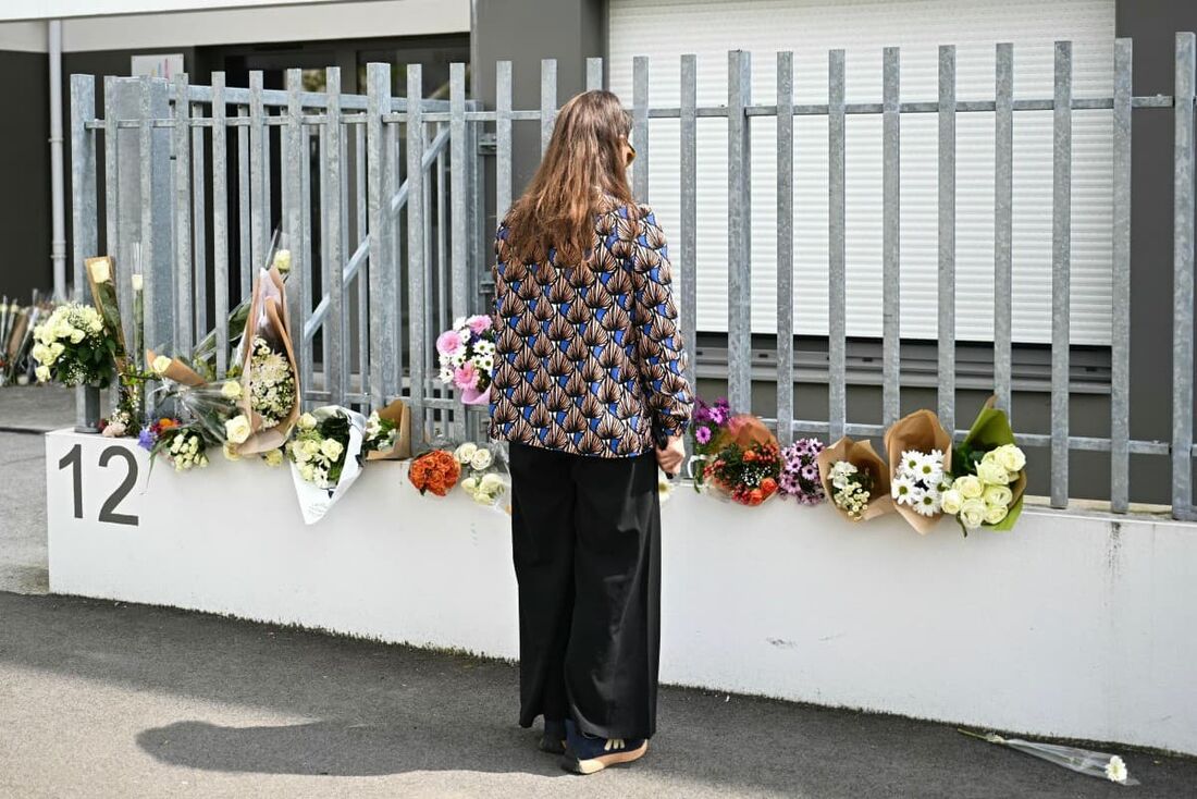Uma menina presta homenagem diante de buquês de flores depositados na entrada da escola Notre-Dame de Toutes-Aides, após um ataque a faca em 24 de abril de 2025. 
