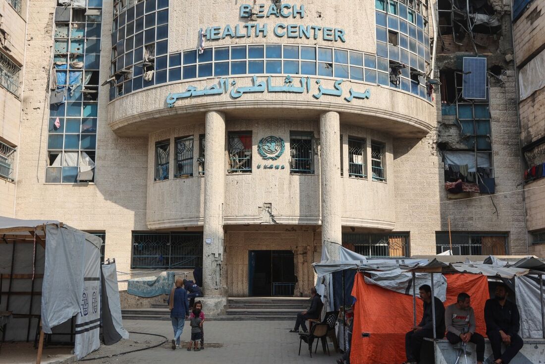 Palestinos deslocados sentam-se em suas tendas improvisadas do lado de fora da clínica administrada pela UNRWA no campo de refugiados de al-Shati