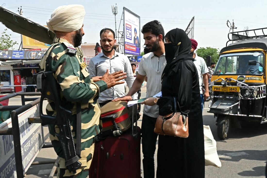 Um membro da Força de Segurança da Fronteira Indiana (BSF) (E) inspeciona o passaporte e os documentos de uma cidadã paquistanesa (D) acompanhada pelo marido, também indiano, enquanto ela se prepara para retornar ao seu país 