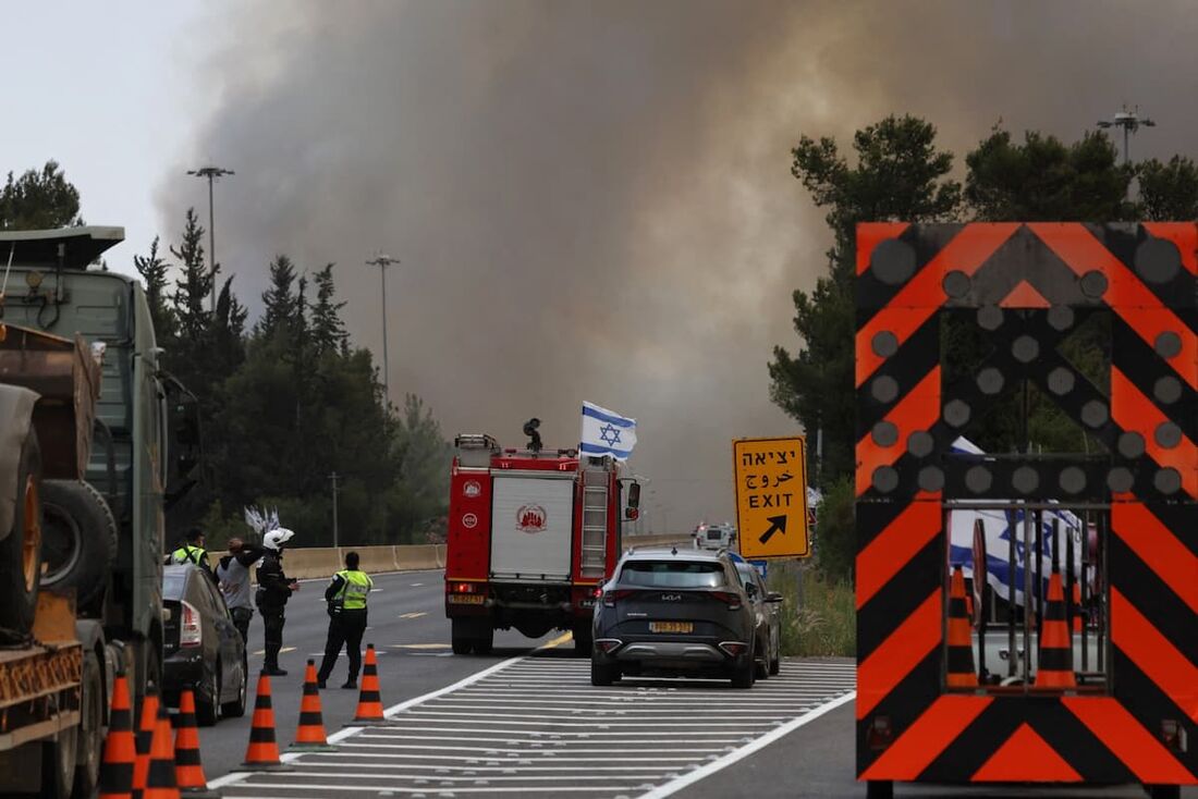 Bombeiros e policiais israelenses se reúnem na rodovia durante um incêndio florestal perto da cidade de Bet Shemesh, no centro de Israel,