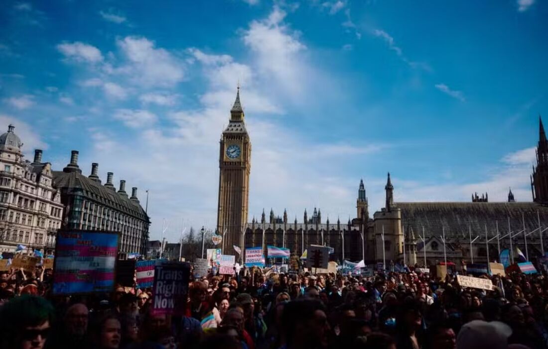 Manifestantes agitam bandeiras e seguram cartazes enquanto se reúnem na Praça do Parlamento, ao lado do Parlamento do Reino Unido