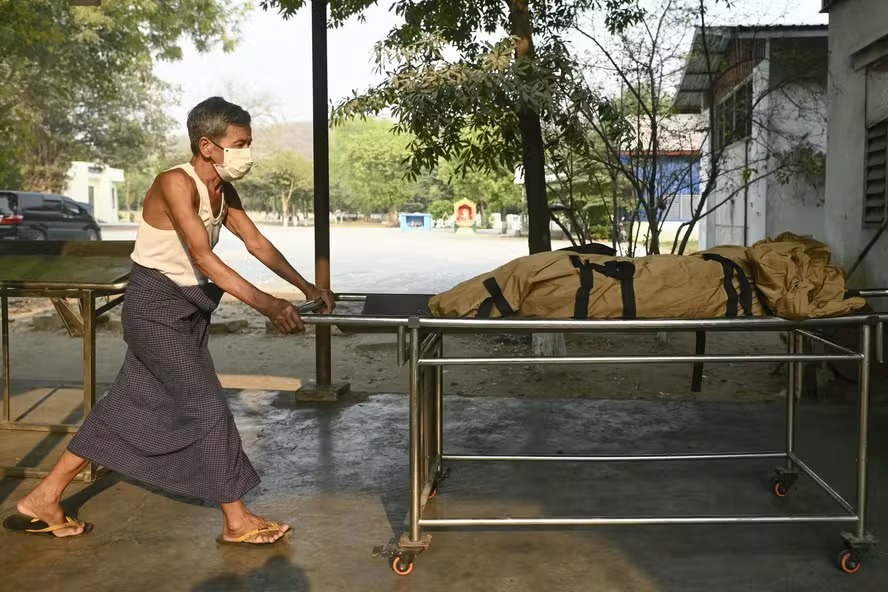 Um trabalhador transporta o corpo de uma vítima para ser cremado no Cemitério Aye Yate Nyein em Kyar Ni Kan, nos arredores de Mandalay