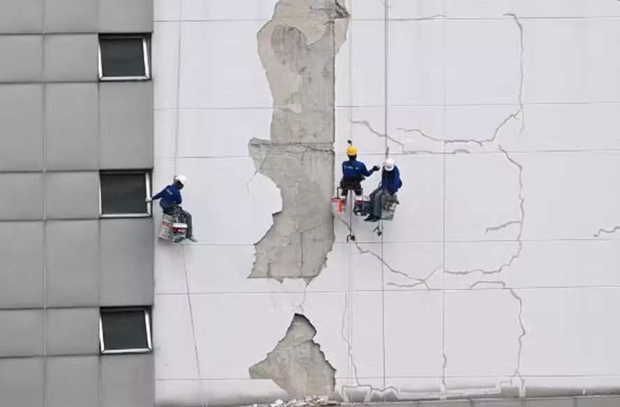 Trabalhadores consertam danos no exterior de um edifício alto em Bangkok após o terremoto de 28 de março 