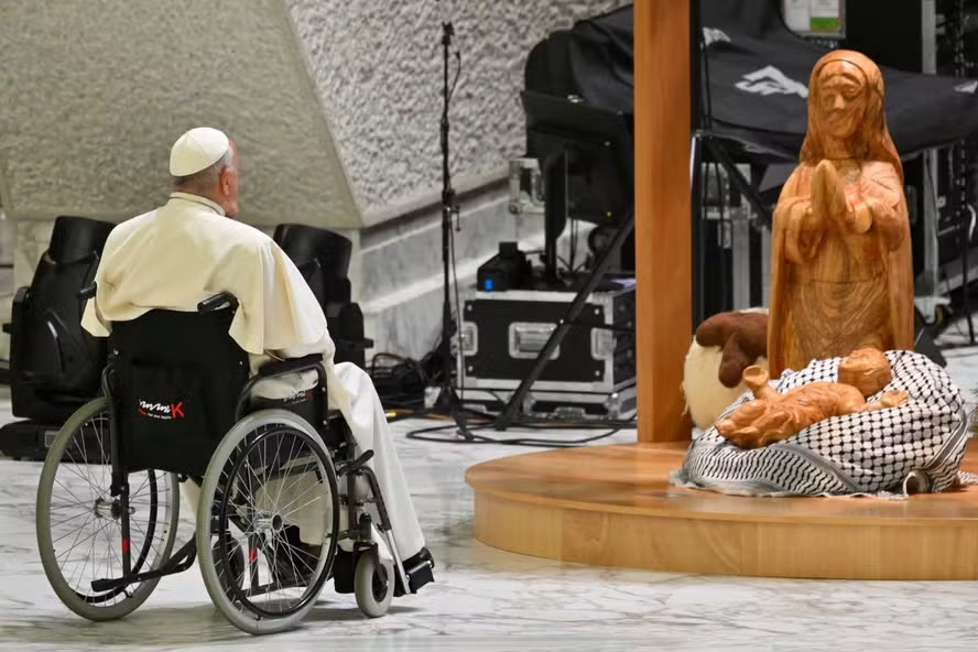 Papa Francisco reza diante de presépio com lenço palestino envolvendo manjedoura de Jesus no Vaticano 
