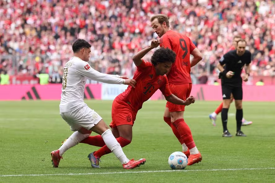 Nadiem Amiri, meio campo do Mainz, em uma dividida com Serge Gnabry e Harry Kane, do Bayern, durante a partida da Bundesliga 2024/25 