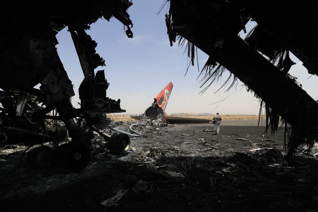 Um rebelde huthi caminha ao lado de um avião destruído no Aeroporto Internacional de Sanaa, em 7 de maio de 2025, um dia após aviões de guerra israelenses a capital do Iêmen