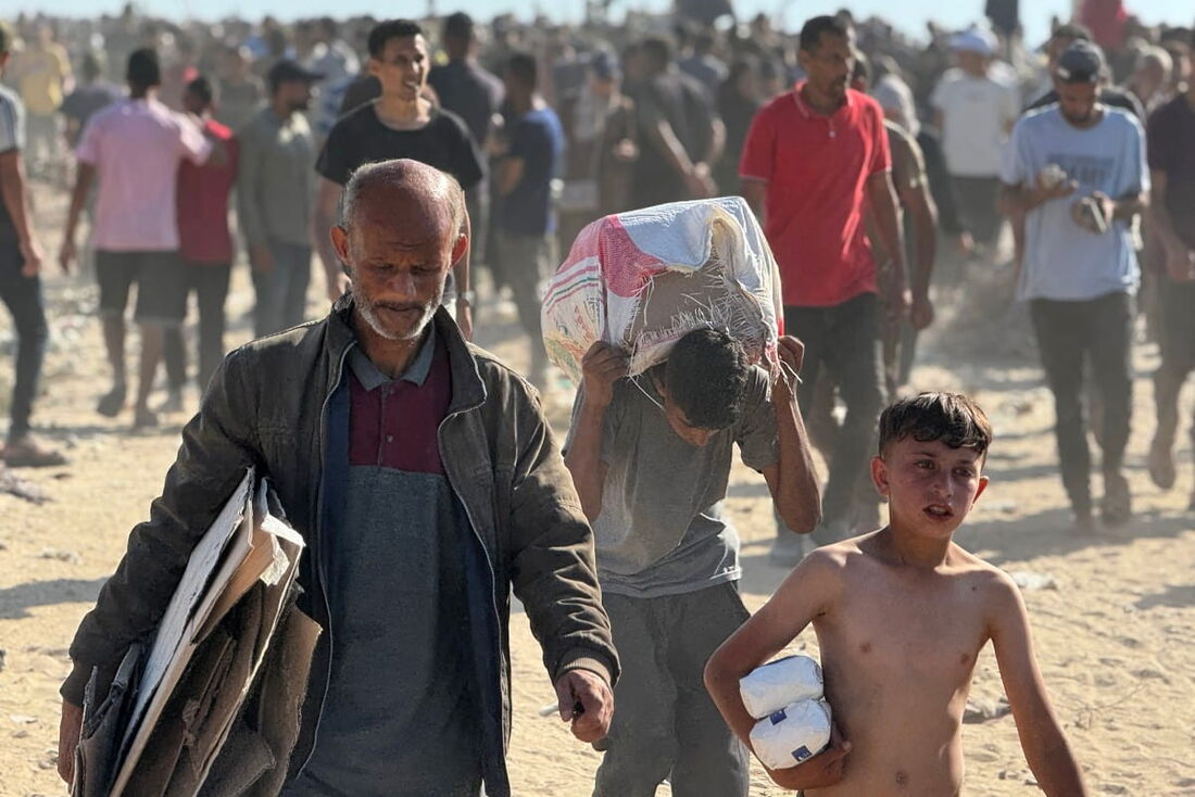 Palestinos deslocados recebem pacotes de alimentos de uma fundação apoiada pelos EUA que se compromete a distribuir ajuda humanitária no oeste de Rafah, no sul da Faixa de Gaza