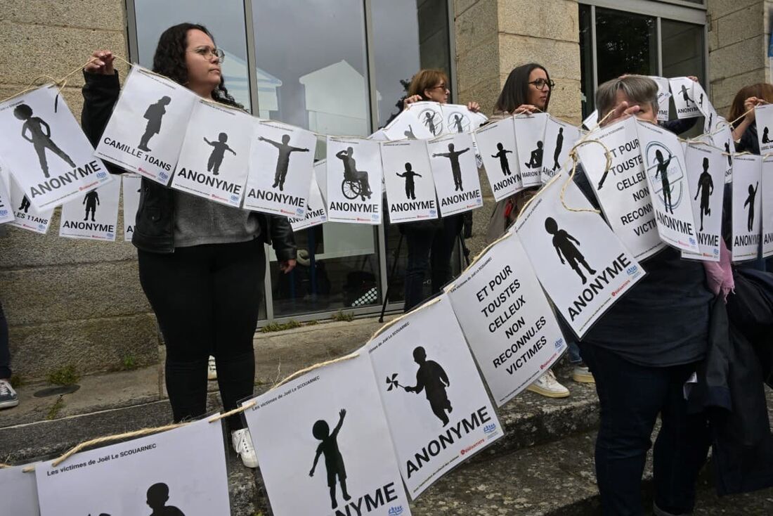 Manifestantes seguram cartazes com os nomes das vítimas no tribunal do julgamento do cirurgião Joël Le Scouarnec em Vannes