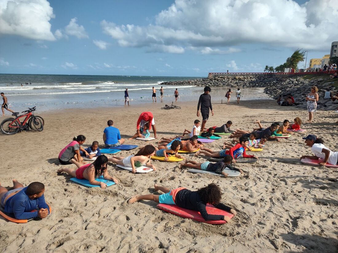 Crianças e jovens com autismo praticam bodyboarding na orla da praia de Olinda