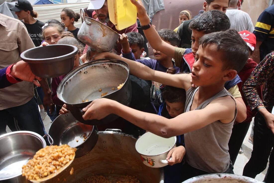Palestinos fazem fila para uma refeição quente em uma cozinha beneficente na Cidade de Gaza