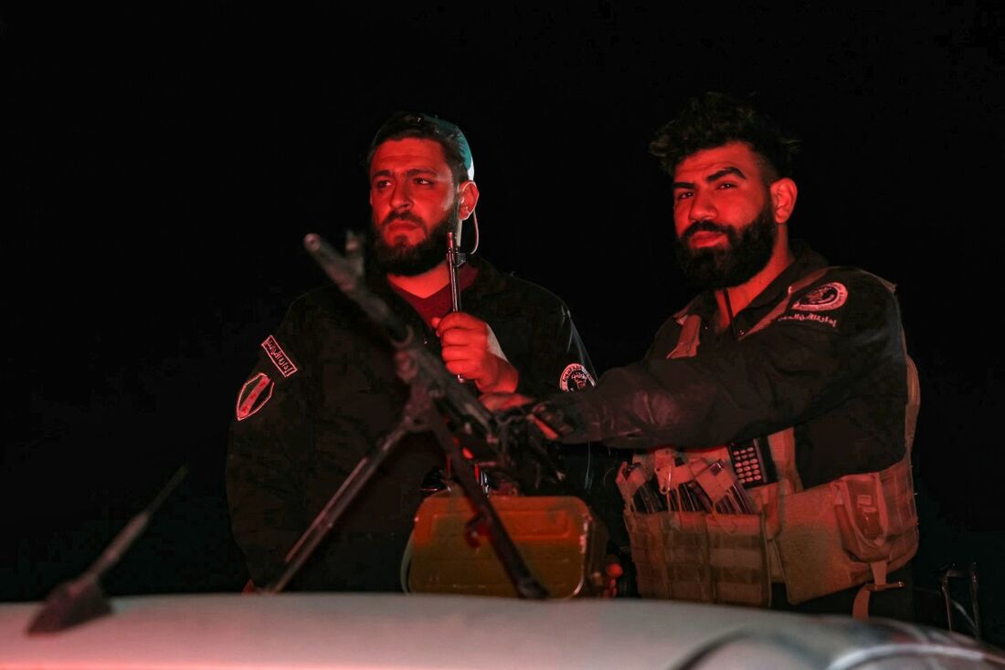 Membros das forças de segurança da Síria montam guarda em um posto de controle na entrada de Jaramana, perto de Damasco