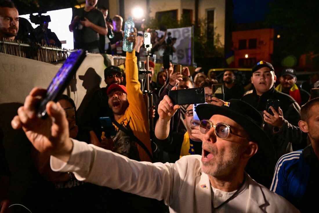 Apoiadores do líder do partido nacionalista soberano Aliança para a União dos Romenos (AUR), George Simion, reagem após o anúncio dos resultados da pesquisa de boca de urna durante o primeiro turno das eleições presidenciais em Bucareste