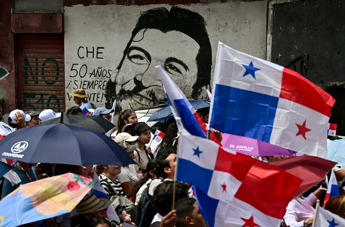 Pessoas marcham em frente a um mural de Ernesto Che Guevara durante uma manifestação convocada por estudantes universitários contra o governo do presidente José Raúl Mulino, na Cidade do Panamá