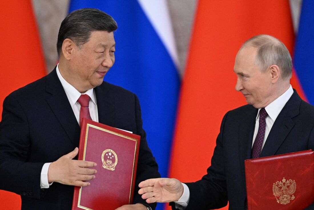 O presidente russo, Vladimir Putin, e seu homólogo chinês, Xi Jinping, trocam documentos durante uma cerimônia de assinatura após suas conversas no Kremlin, em Moscou