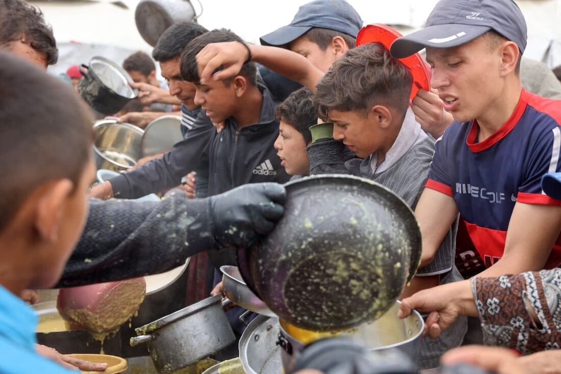Jovens palestinos recebendo uma ração de comida quente no campus da Universidade Islâmica na Cidade de Gaza