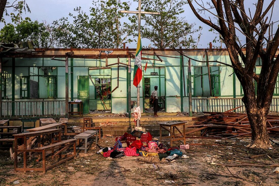 Um homem olha para dentro de um prédio escolar danificado por um bombardeio realizado pelo exército de Mianmar na vila de Ohe Htein Twin