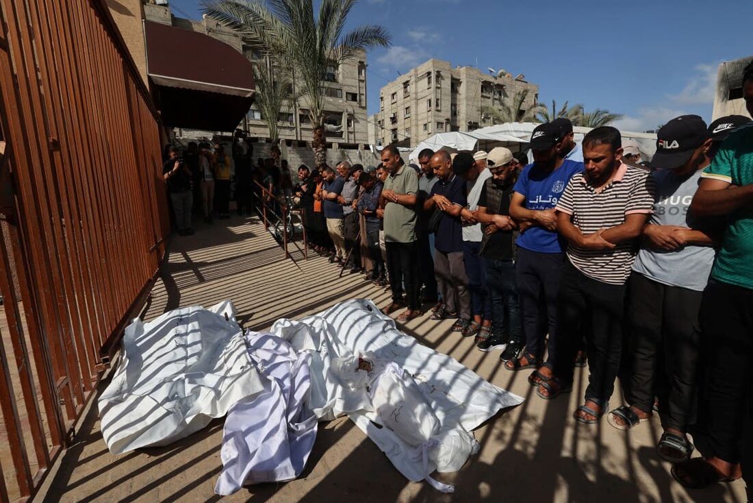 Pessoas em frente a corpos das vítimas de um ataque israelense em Khan Yunis, no sul da Faixa de Gaza, em 14 de maio de 2025.