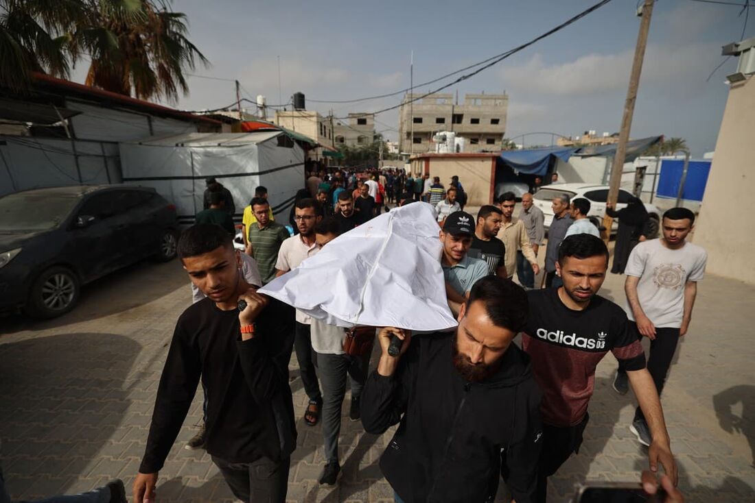 Palestinos com o corpo de uma vítima de ataques israelenses, no necrotério de um hospital no centro da Faixa de Gaza