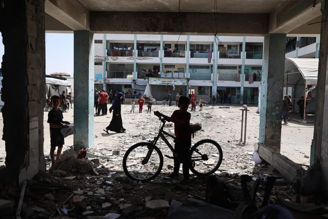 Palestino sobre destroços no pátio de uma escola atingida diretamente por ataques aéreos israelenses no campo de refugiados de Nuseirat
