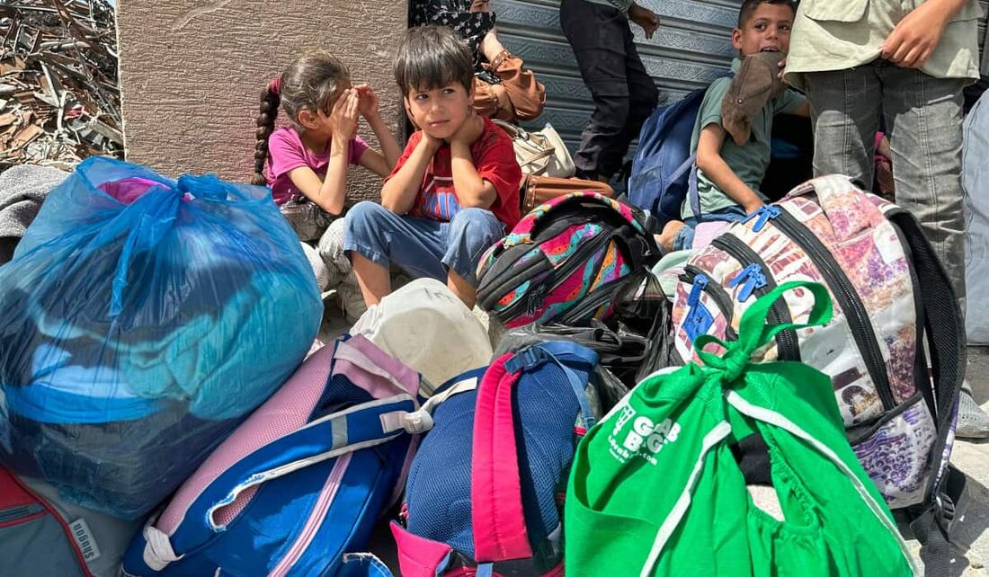 Palestinos aguardando transporte após ordens de evacuação israelenses para Khan Yunis