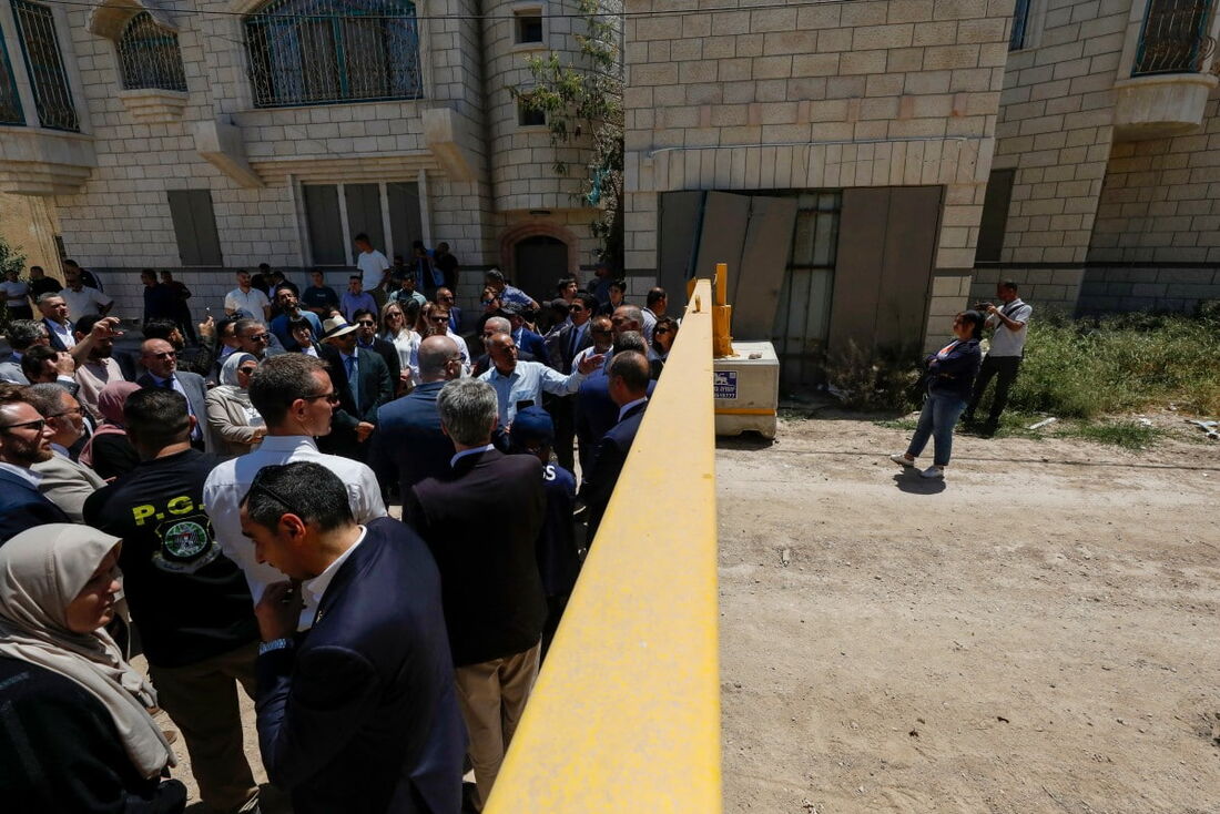 Membros de uma delegação diplomática da União Europeia posam atrás de um portão na entrada leste do campo de Jenin durante uma visita à cidade, em meio a uma ofensiva militar israelense na Cisjordânia ocupada. 
