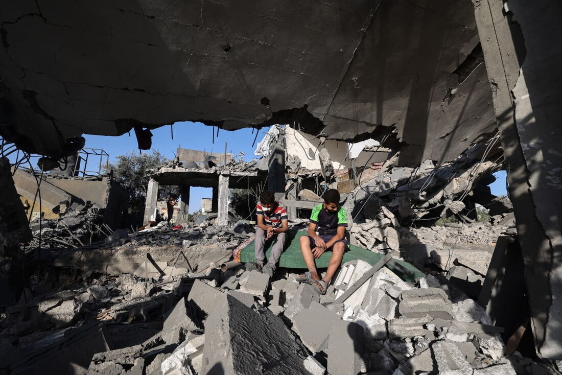 Meninos palestinos sentam-se sobre os escombros de uma casa alvo de um ataque israelense no campo de refugiados de Nuseirat, no centro da Faixa de Gaza