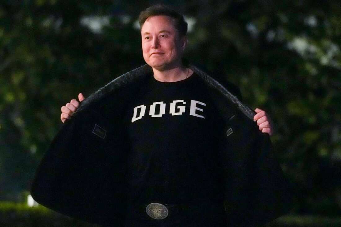 Elon Musk exibe uma camisa com a inscrição "DOGE" enquanto caminha pelo gramado sul da Casa Branca