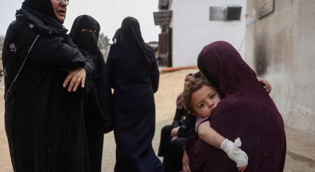 Mãe carrega criança ferida no Hospital al-Shifa, em Gaza 