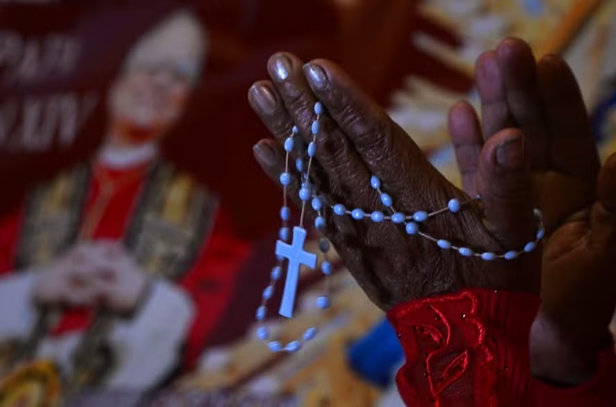 Uma mulher reza ao lado da imagem de Robert Francis Prevost, que se tornou Papa Leão XIV em 8 de maio de 2025, em frente à catedral de Chiclayo, no norte do Peru 