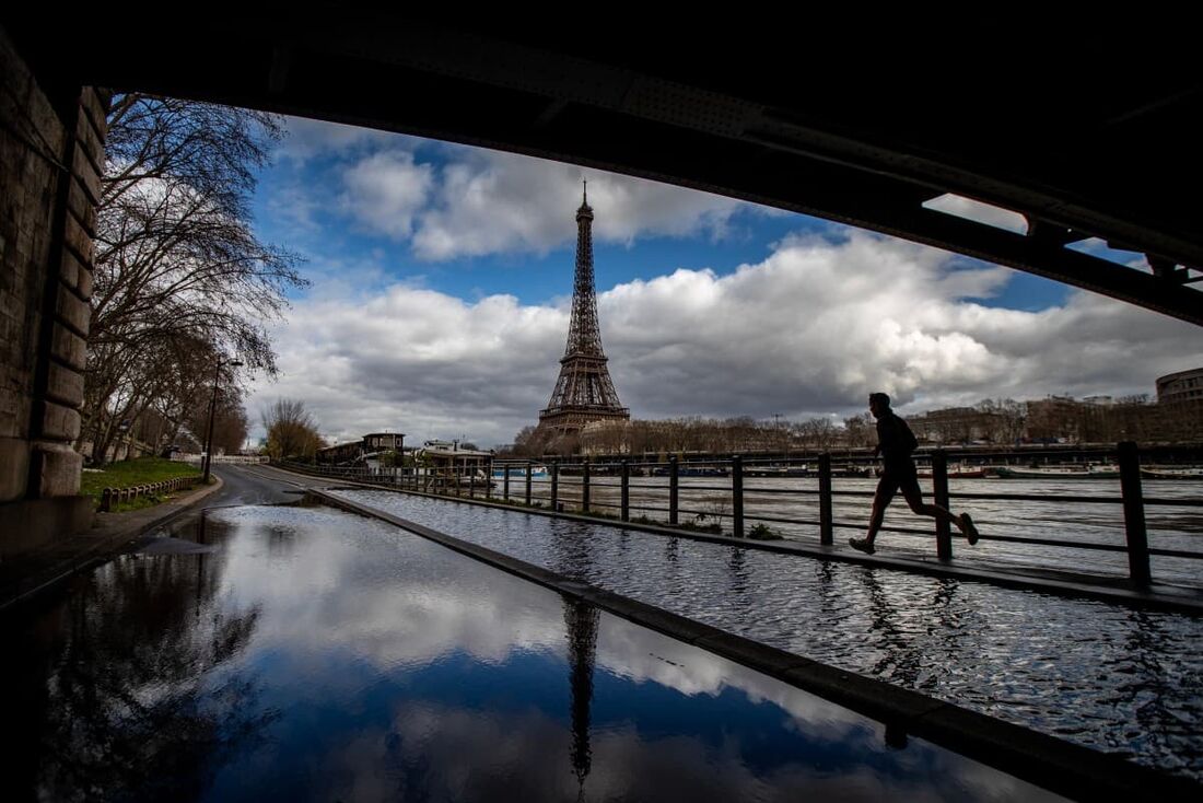 Um homem corre nas margens inundadas do rio Sena, com a Torre Eiffel ao fundo, em Paris