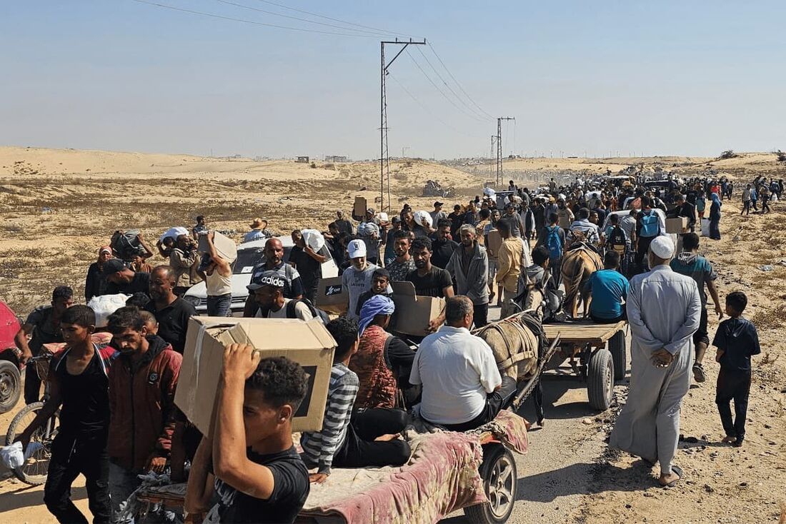 Palestinos deslocados caminham por uma estrada para receber pacotes de ajuda humanitária de uma fundação apoiada pelos EUA em Rafah