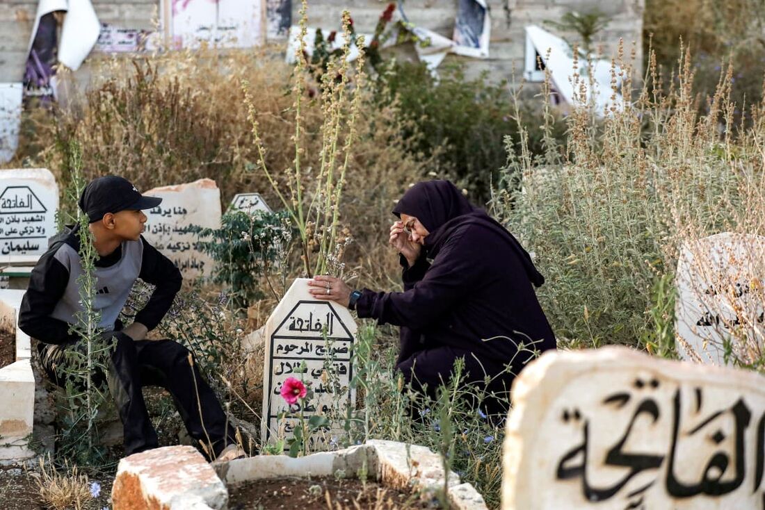 Uma mulher reage ao túmulo de um ente querido